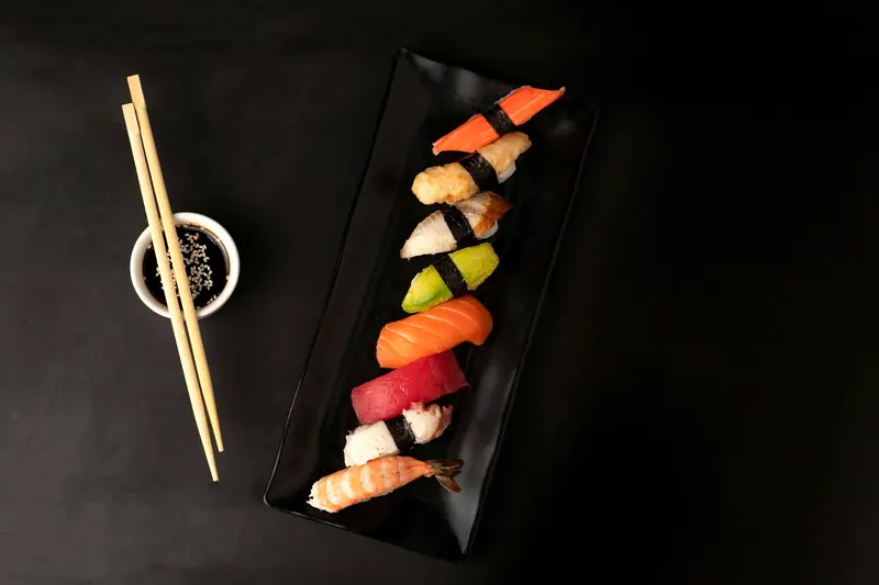 Assorted sushi on a black plate with chopsticks