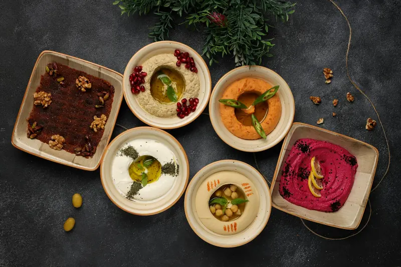 Levantine mezze: hummus, moutabal and muhammara on a dark table