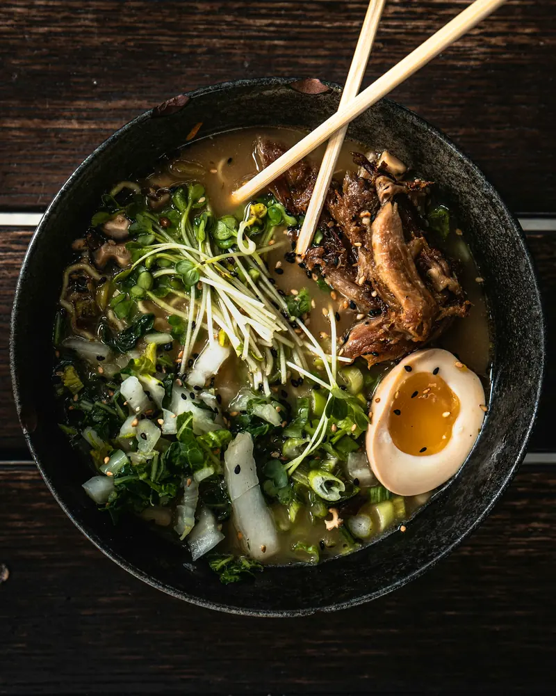 A bowl of ramen with egg and greens