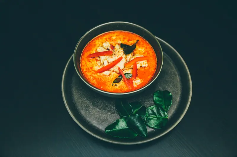 Thai tom yum soup in a dark bowl